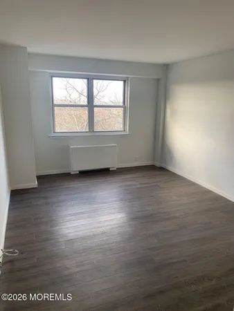 an empty room with wooden floor & closet area