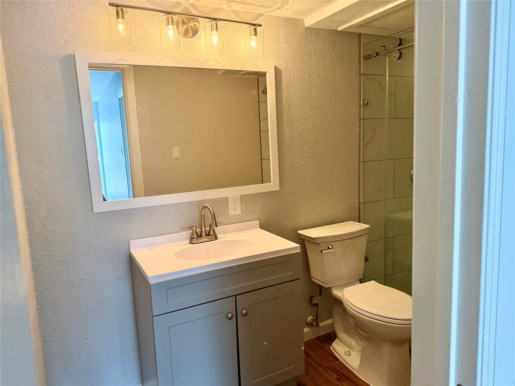 12818 Midway Road, Unit 1089 Dallas, TX 75244 - Photo 18 of 18 a bathroom with a toilet a sink a mirror and shower