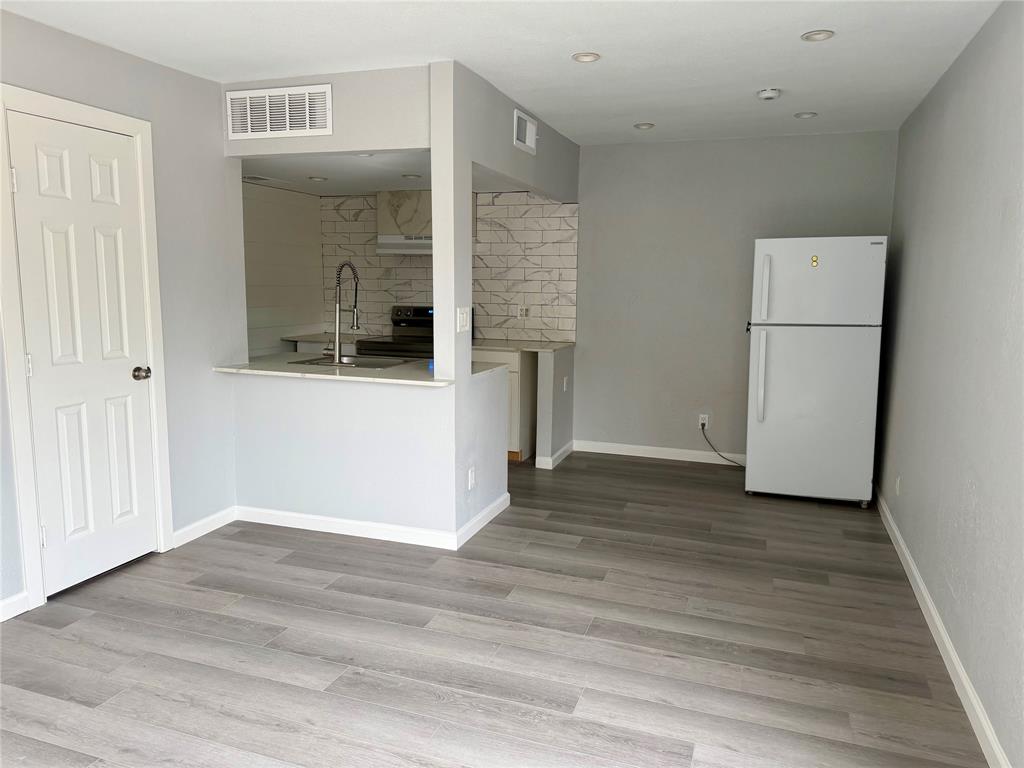 12818 Midway Road, Unit 1089 Dallas, TX 75244 - Photo 5 of 18 a view of a room with wooden floor and a white cabinet