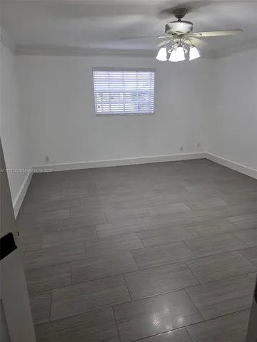 an empty room with wooden floor fan and window