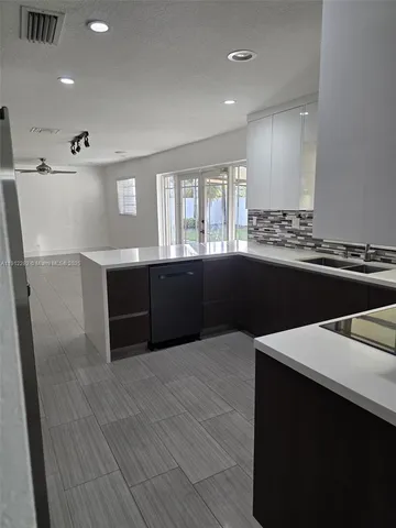 a large kitchen with stainless steel appliances a sink dishwasher a stove and white cabinets next to a window