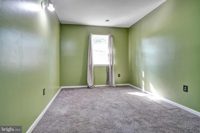 a view of an empty room with a window and a bathroom