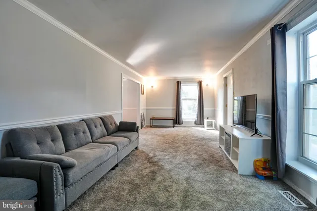 a living room with furniture a flat screen tv and a large window