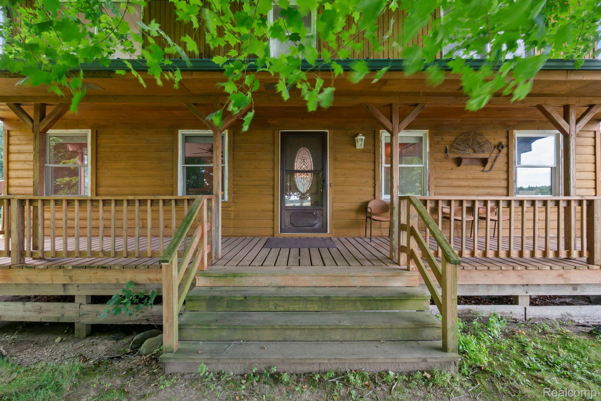 76565 McFadden Road Armada, MI 48005 - Photo 2 of 95 Inviting porch with wood-finish decking and steps, white railing with black balusters, and a black front door with an oval glass insert