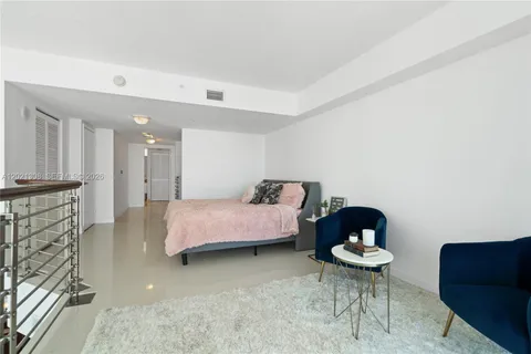 a bedroom with a bed and a chair with the bookshelf