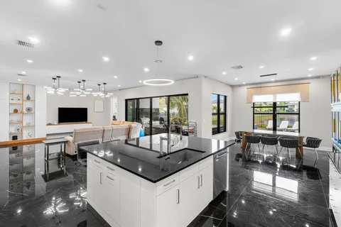 a room with stainless steel appliances kitchen island granite countertop a sink and white cabinets