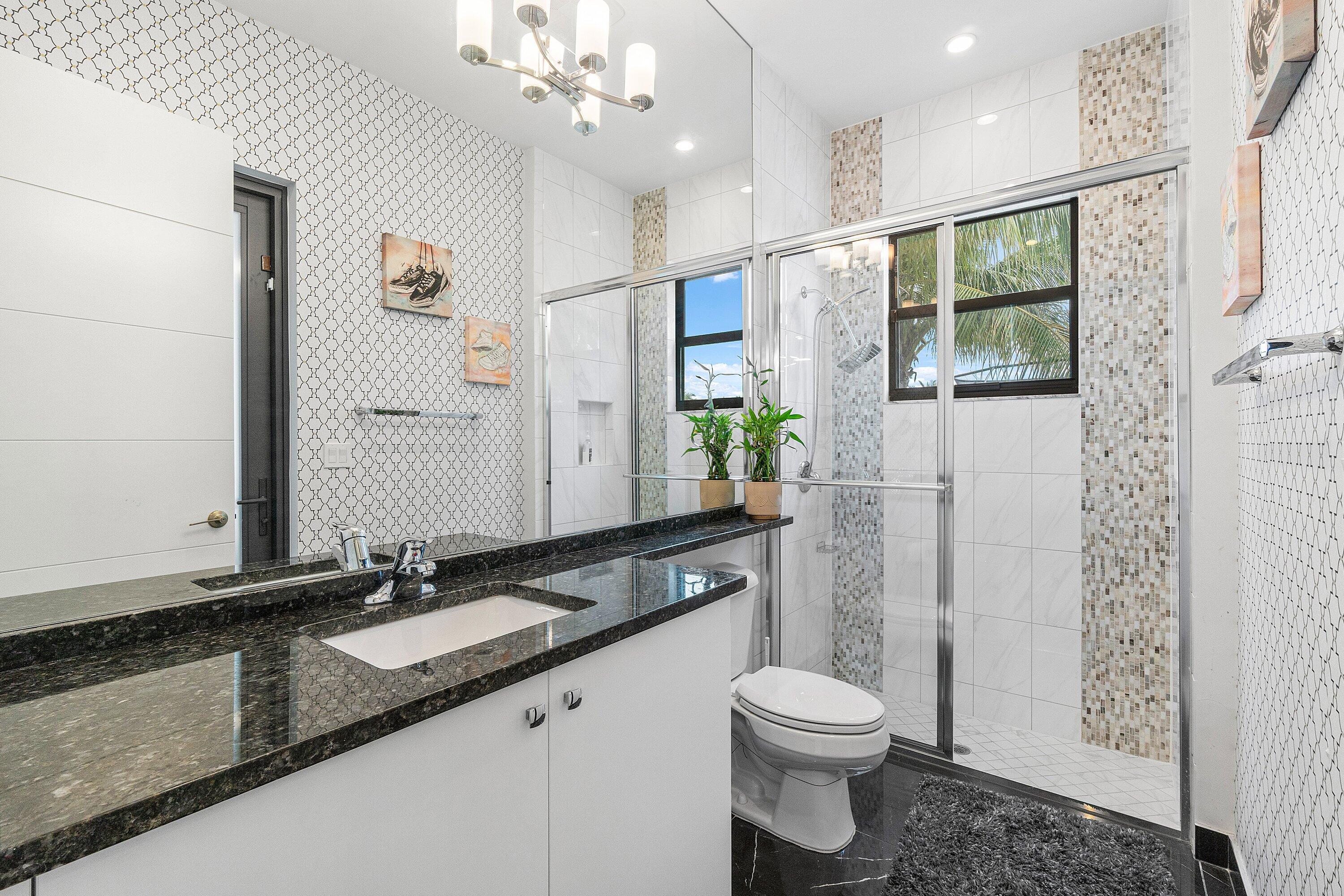 17238 Teton River Road Boca Raton, FL 33496 - Photo 23 of 67 a bathroom with a granite countertop sink a toilet a mirror a vanity and shower