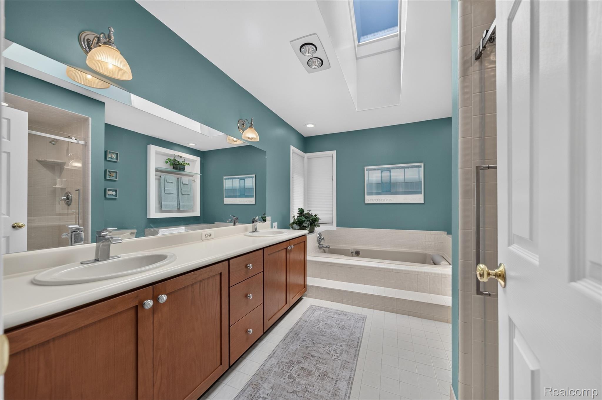 1236 Chaffer Drive Rochester, MI 48306 - Photo 33 of 76 Spacious bathroom featuring a dual vanity with wood cabinetry, a large built-in mirror, a skylight, and a tiled soaking tub