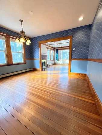 a view of an empty room with window and wooden floor