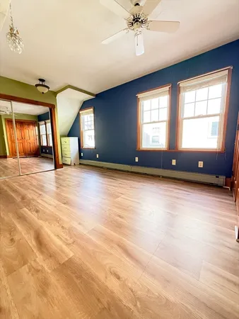 a view of an empty room with a window and wooden floor