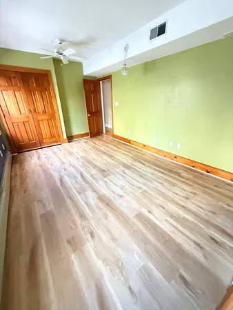 a view of a room with wooden floor and a ceiling fan