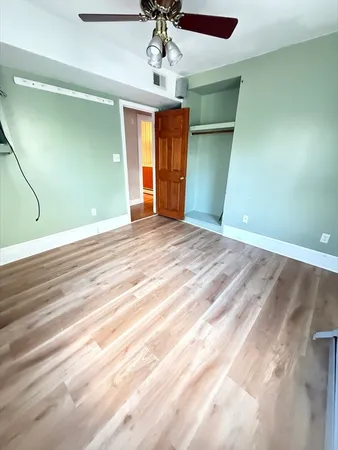 a view of an empty room with window and chandelier fan