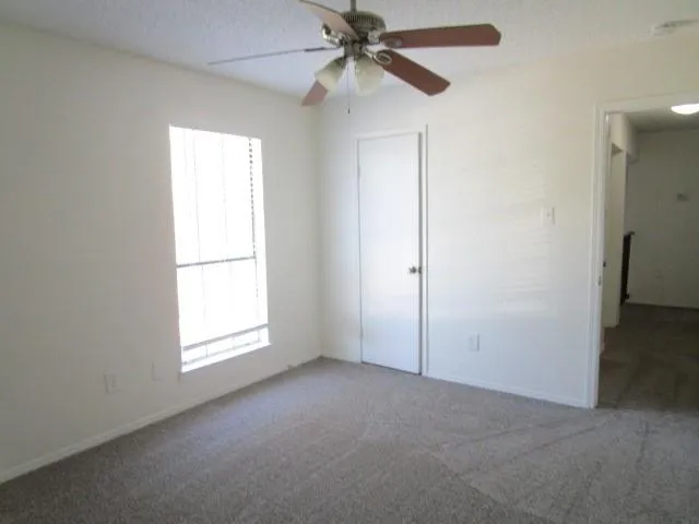 an empty room with windows and fan