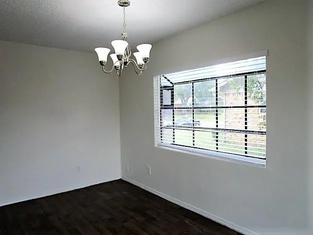 a view of a chandelier fan and wooden floor in an empty room