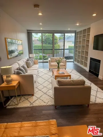 a living room with furniture floor to ceiling window and a flat screen tv