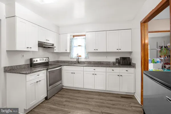 a kitchen with stainless steel appliances granite countertop a stove a sink and white cabinets
