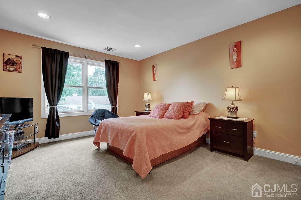 11 Kenmore Road Edison, NJ 08817 - Photo 19 of 40 a spacious bedroom with a bed and a flat tv screen on dresser
