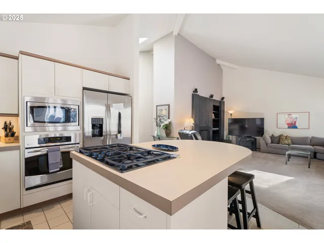 a kitchen view with stainless steel appliances a stove a sink dishwasher and white cabinets with wooden floor