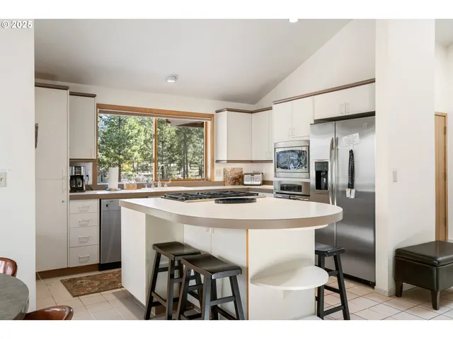 a kitchen with stainless steel appliances kitchen island granite countertop a table chairs and a refrigerator