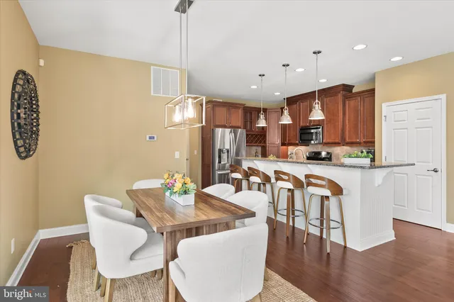 a kitchen with stainless steel appliances granite countertop a refrigerator a sink dishwasher and a stove with wooden floor