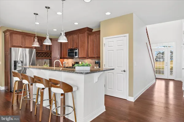 a kitchen with stainless steel appliances granite countertop a stove top oven a sink a dining table and chairs