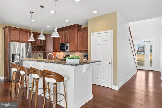 a kitchen with stainless steel appliances granite countertop a stove top oven a sink a dining table and chairs