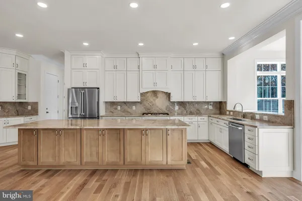 a kitchen with stainless steel appliances granite countertop a stove a sink dishwasher and a refrigerator with wooden floor