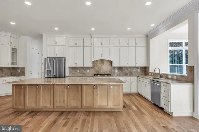 a kitchen with stainless steel appliances granite countertop a stove a sink dishwasher and a refrigerator with wooden floor