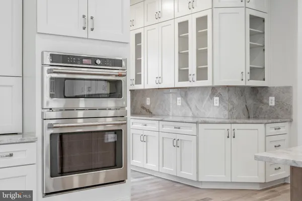a kitchen with granite countertop white cabinets stainless steel appliances and a counter space