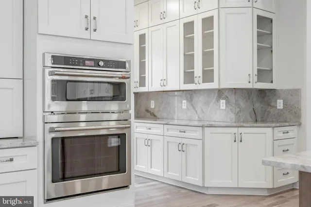 a kitchen with granite countertop white cabinets stainless steel appliances and a counter space