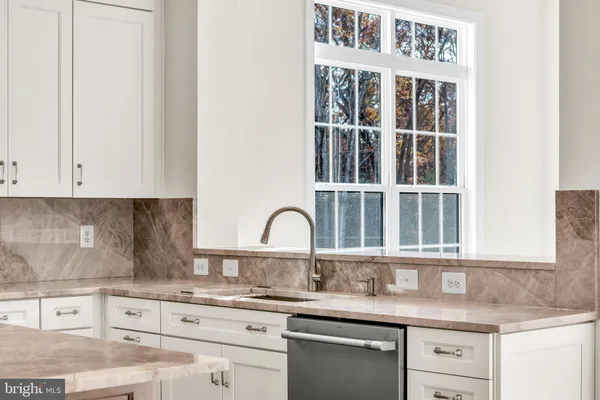 a kitchen with granite countertop white cabinets and window