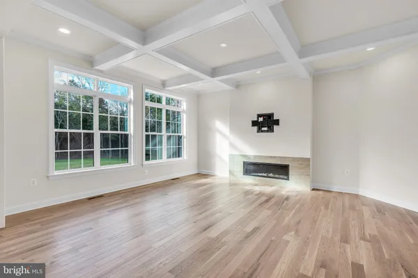 an empty room with windows a fireplace and wooden floor