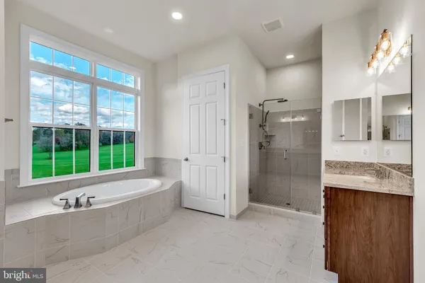 a bathroom with a granite countertop tub sink and mirror