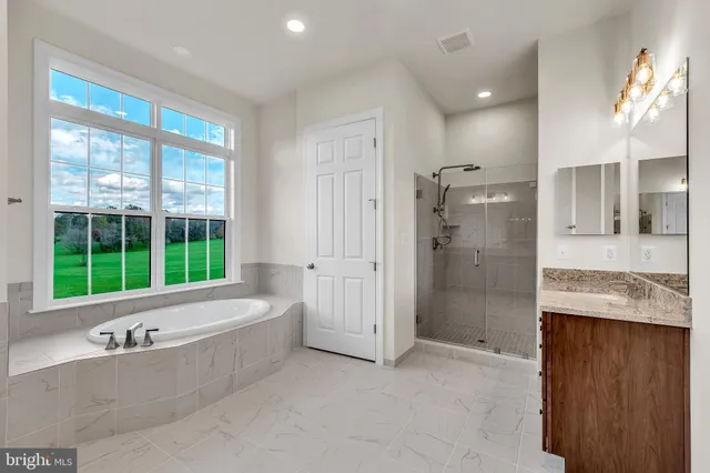 a bathroom with a granite countertop tub sink and mirror