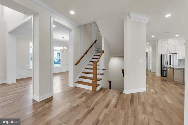 a view of a hallway with wooden floor and a kitchen