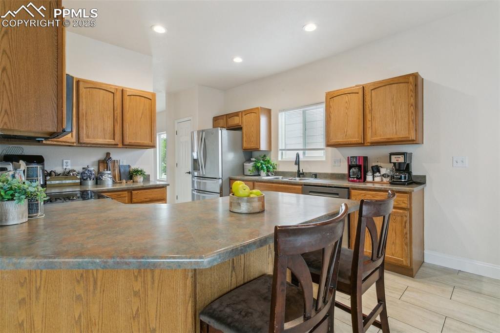 12229 Crystal Downs Road Peyton, CO 80831 - Photo 15 of 47 a kitchen with stainless steel appliances granite countertop a stove top oven a sink a dining table and chairs with wooden floor