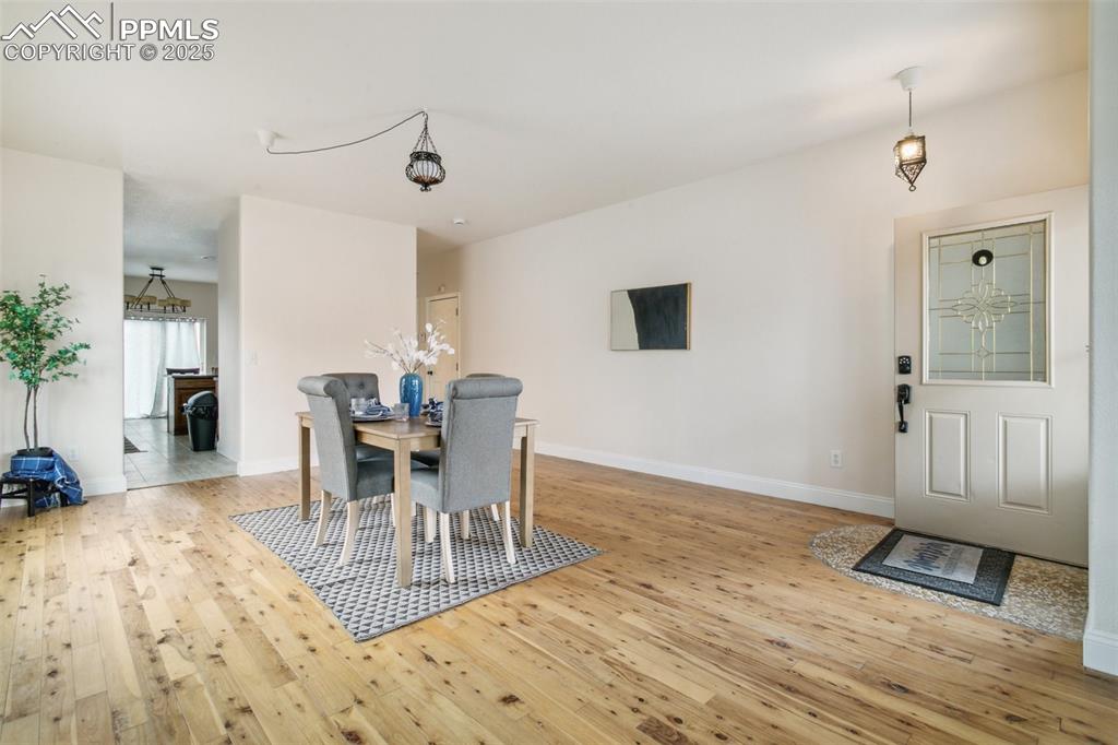 12229 Crystal Downs Road Peyton, CO 80831 - Photo 5 of 47 a dining room with wooden floor a chandelier a wooden table and chairs