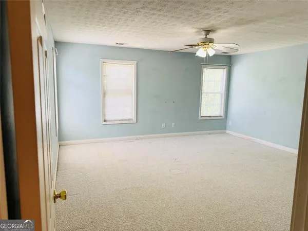 en empty room with windows and chandelier fan
