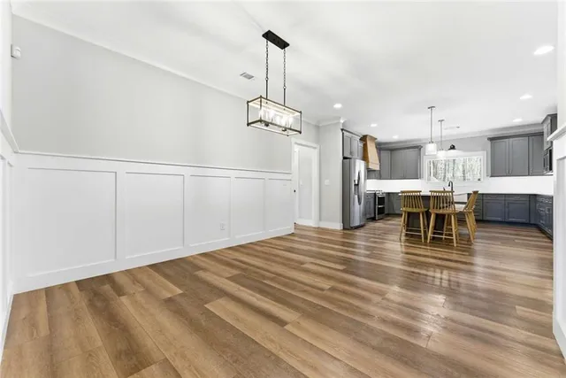 a view of a room with wooden floor kitchen view and a chandelier