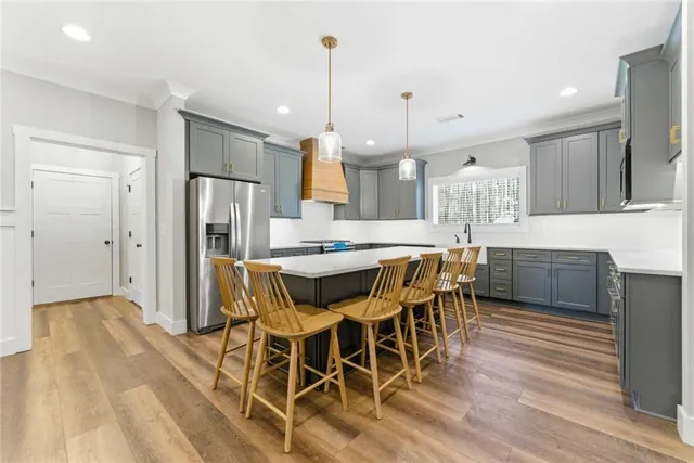 a kitchen with stainless steel appliances a refrigerator a sink dishwasher a stove and a dining table with wooden floor