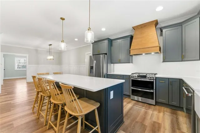 a kitchen with stainless steel appliances granite countertop a stove a refrigerator a sink a dining table and chairs with wooden floor