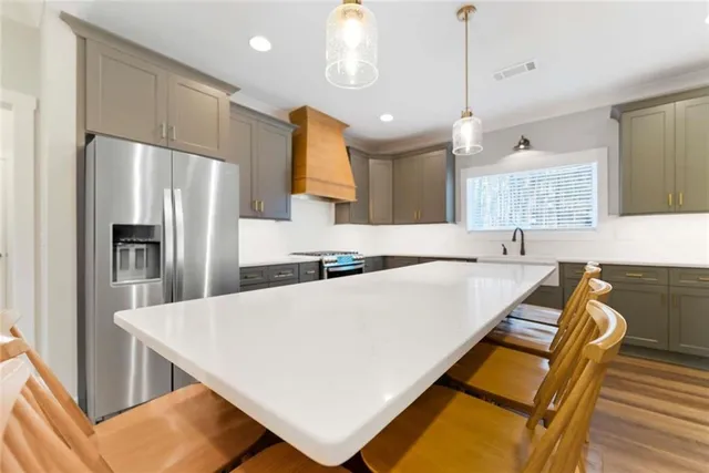 a large kitchen with kitchen island a stove a sink a center island a refrigerator wooden floor and a window