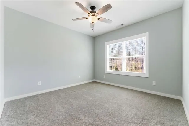 an empty room with windows and ceiling fan