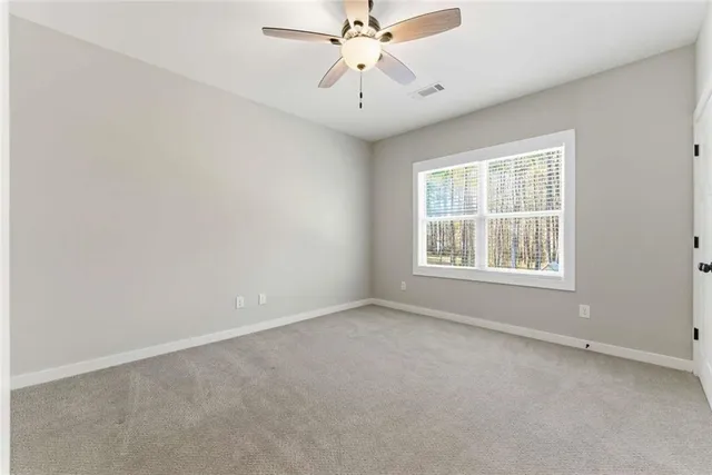 an empty room with chandelier fan and windows
