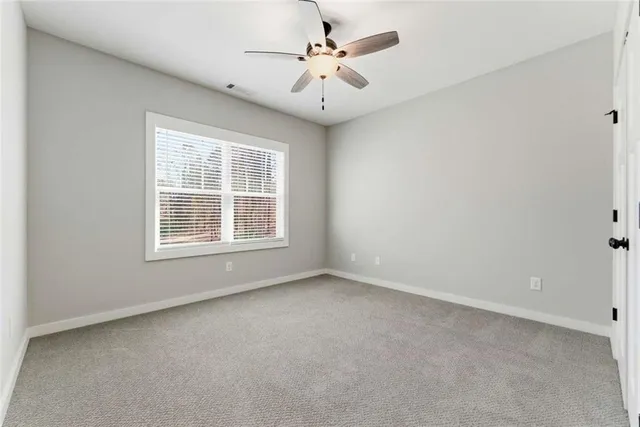 an empty room with windows and ceiling fan