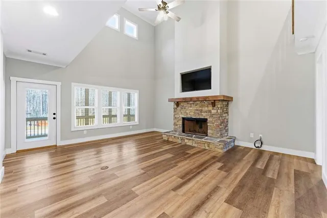 a view of an empty room with wooden floor fireplace and a window