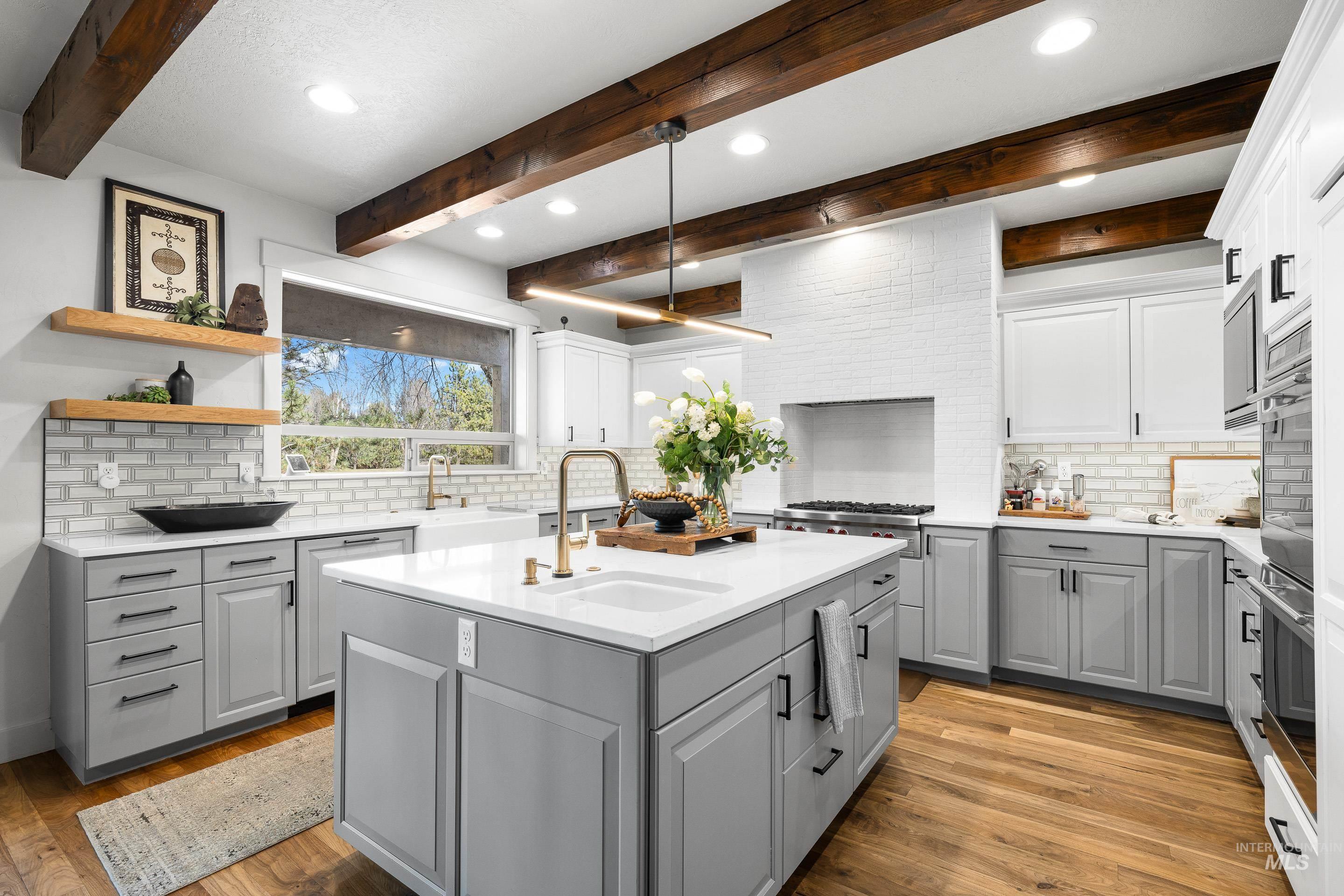 1166 East Rivers End Drive Eagle, ID 83616 - Photo 12 of 50 Kitchen featuring tasteful backsplash, gray cabinets, a center island with sink, wood finished floors, and open shelves
