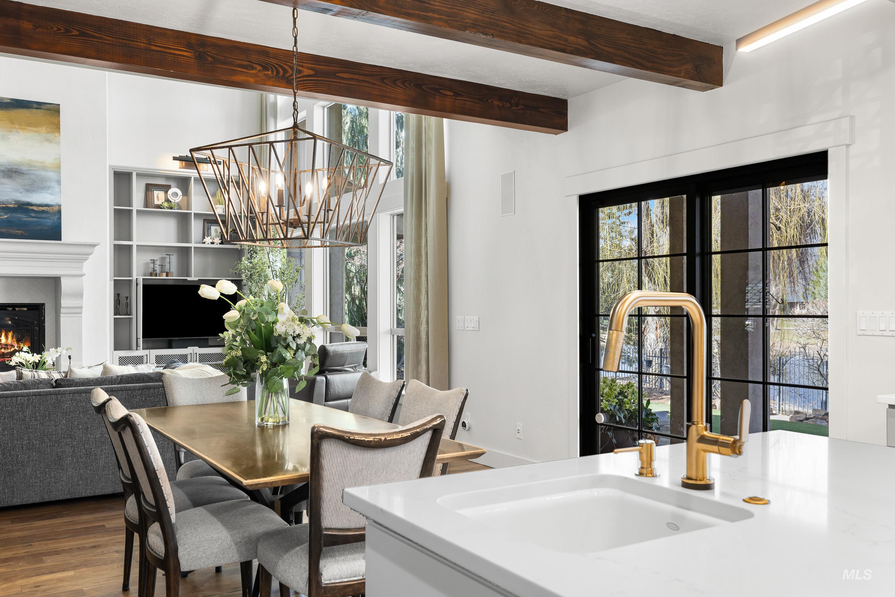 1166 East Rivers End Drive Eagle, ID 83616 - Photo 16 of 50 Dining room featuring a chandelier, a warm lit fireplace, beam ceiling, and wood finished floors