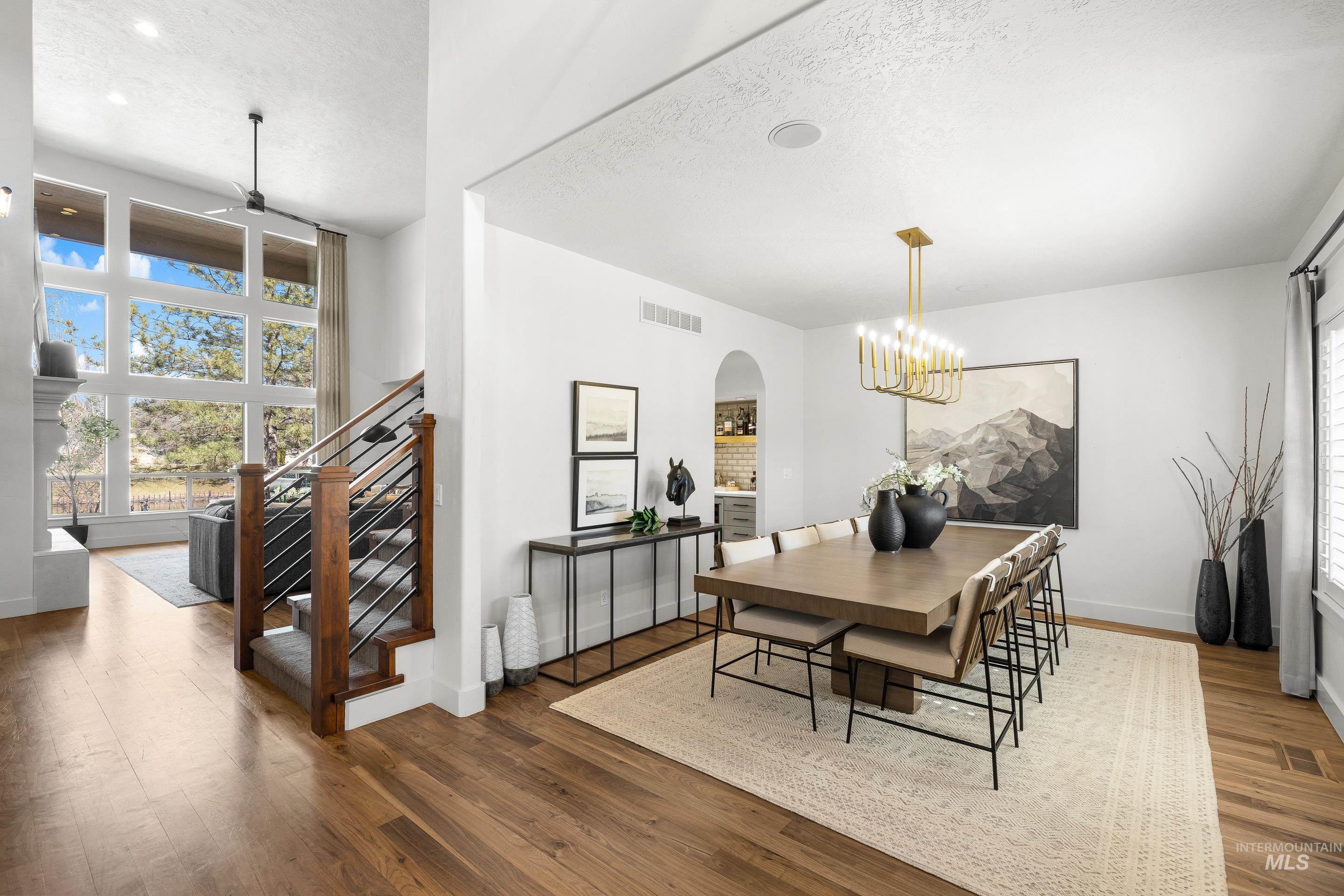 1166 East Rivers End Drive Eagle, ID 83616 - Photo 19 of 50 Dining space featuring arched walkways, hardwood / wood-style floors, a textured ceiling, a ceiling fan, and a chandelier