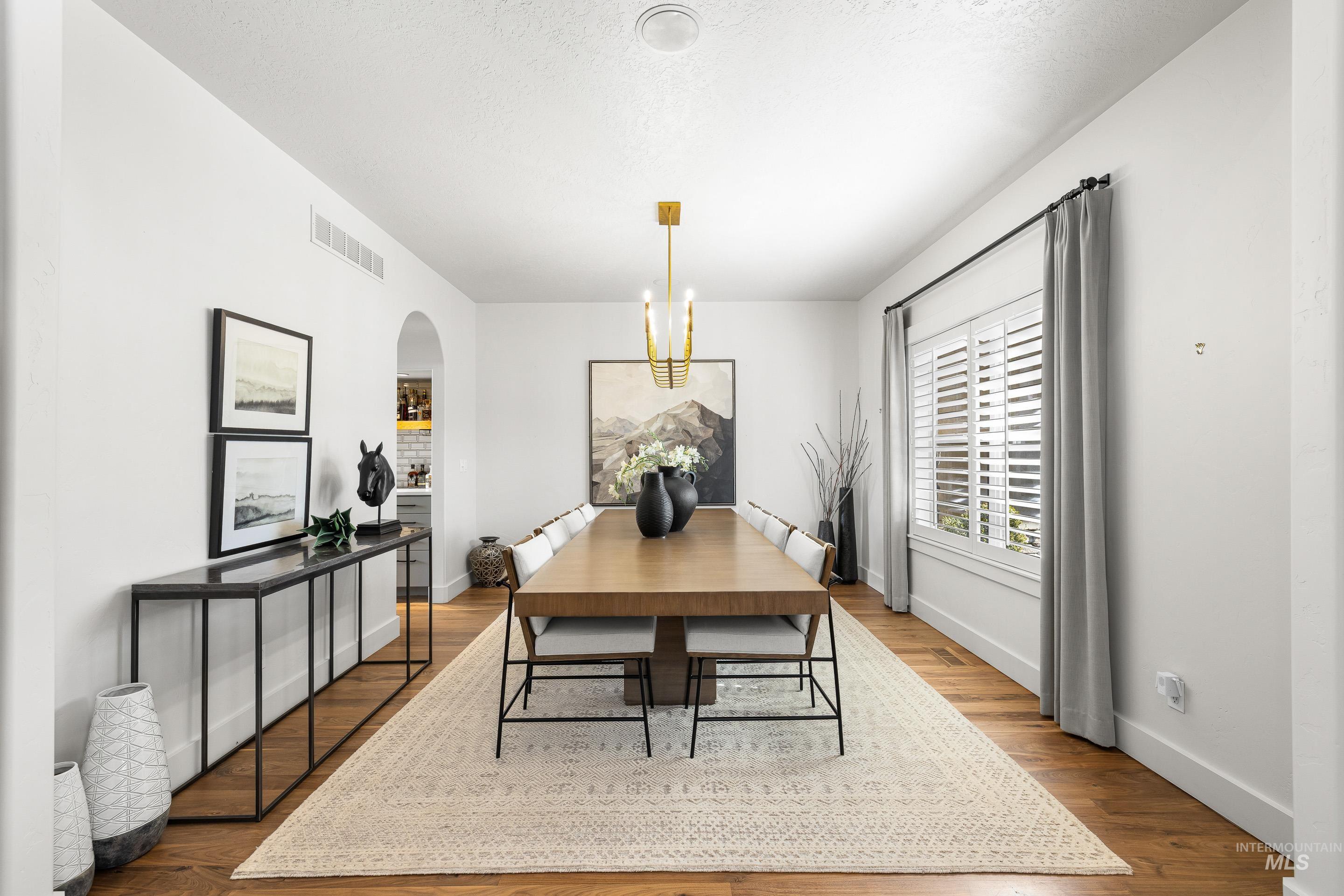 1166 East Rivers End Drive Eagle, ID 83616 - Photo 20 of 50 Dining space featuring arched walkways, suspended lighting, and dark wood-style flooring
